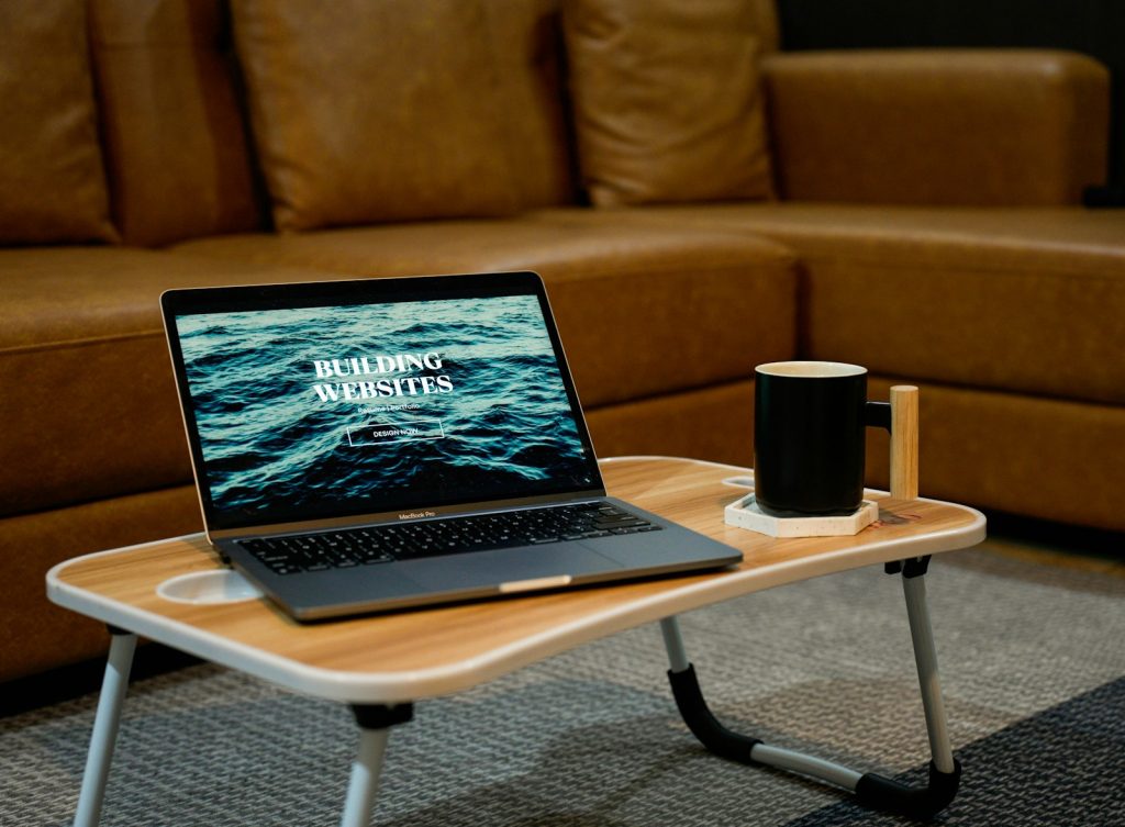 Laptop on table showing Building Websites next to a coffee mug in a cosy lounge setting