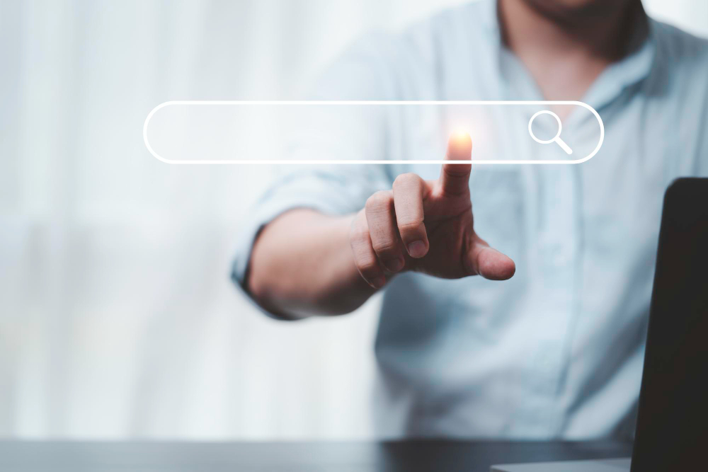 Person interacting with digital search bar, finger pointing at screen symbolising online information search